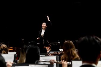A female conductor leading the University Orchestra.
