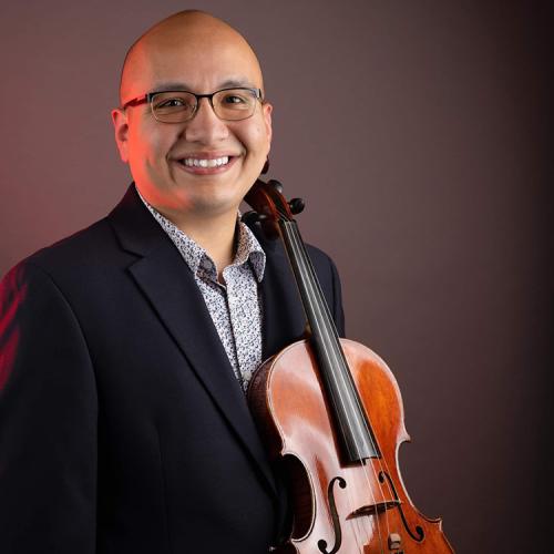 Ruben Balboa holds his violin and looks happily into camera