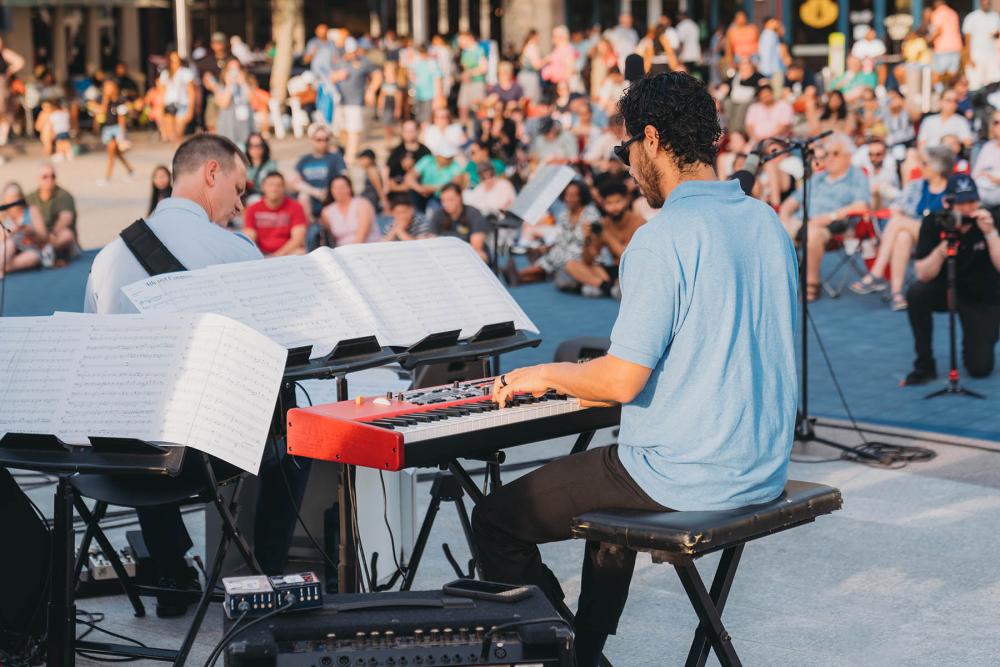  David Mesquitic playing the piano with an audience in the background