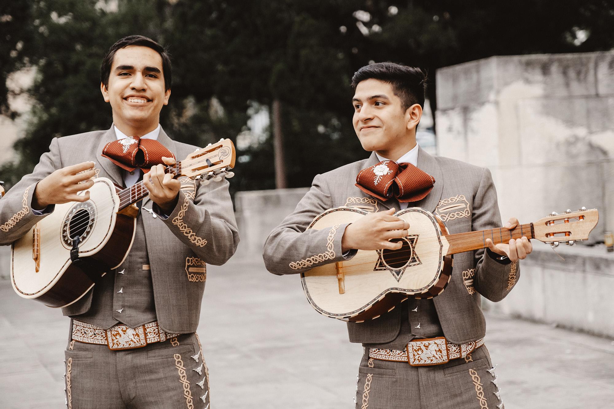 Guitarists smile while performing with the Mariachi