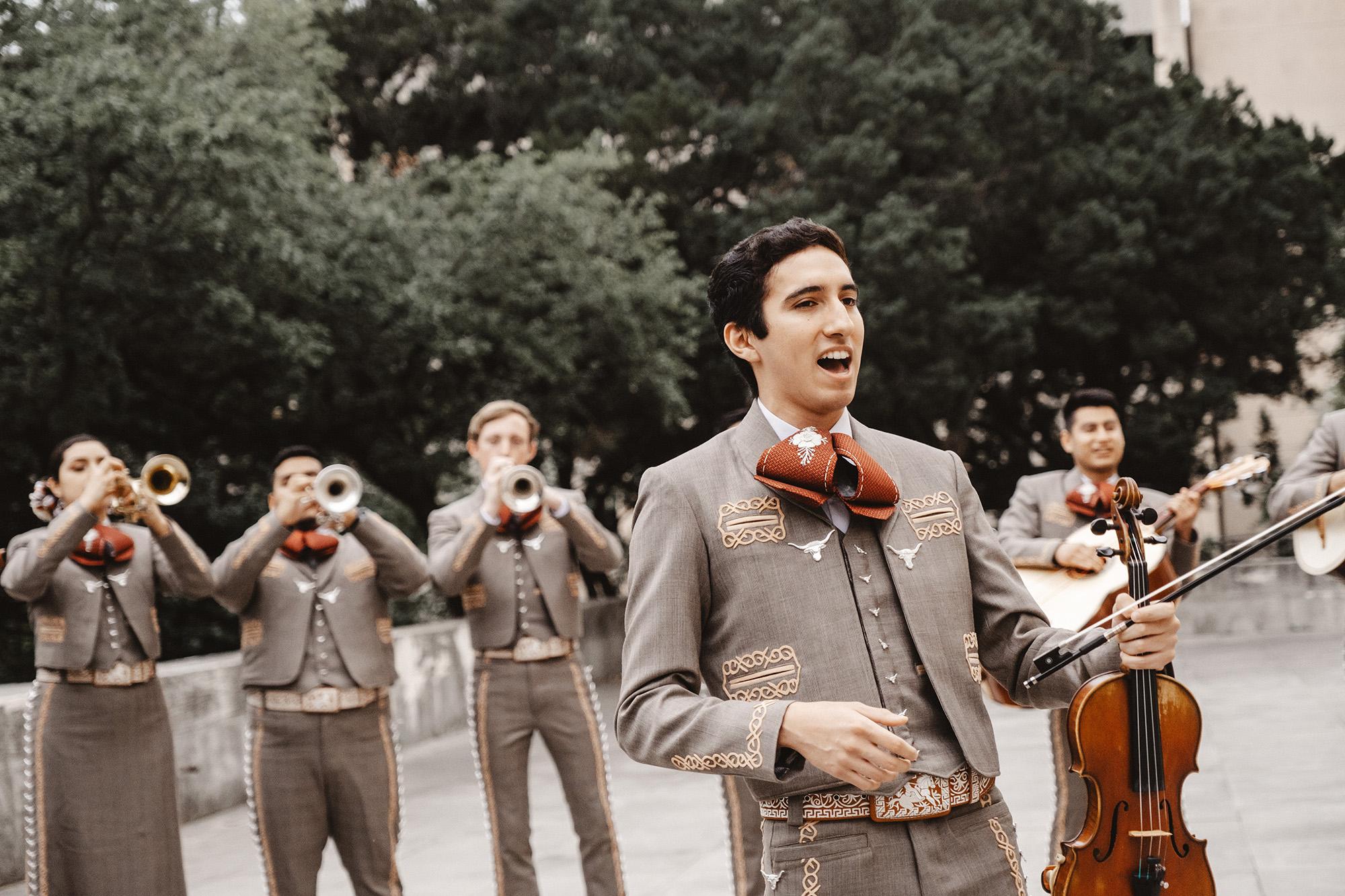 A Member of Mariachi Sings while player accompany behind him