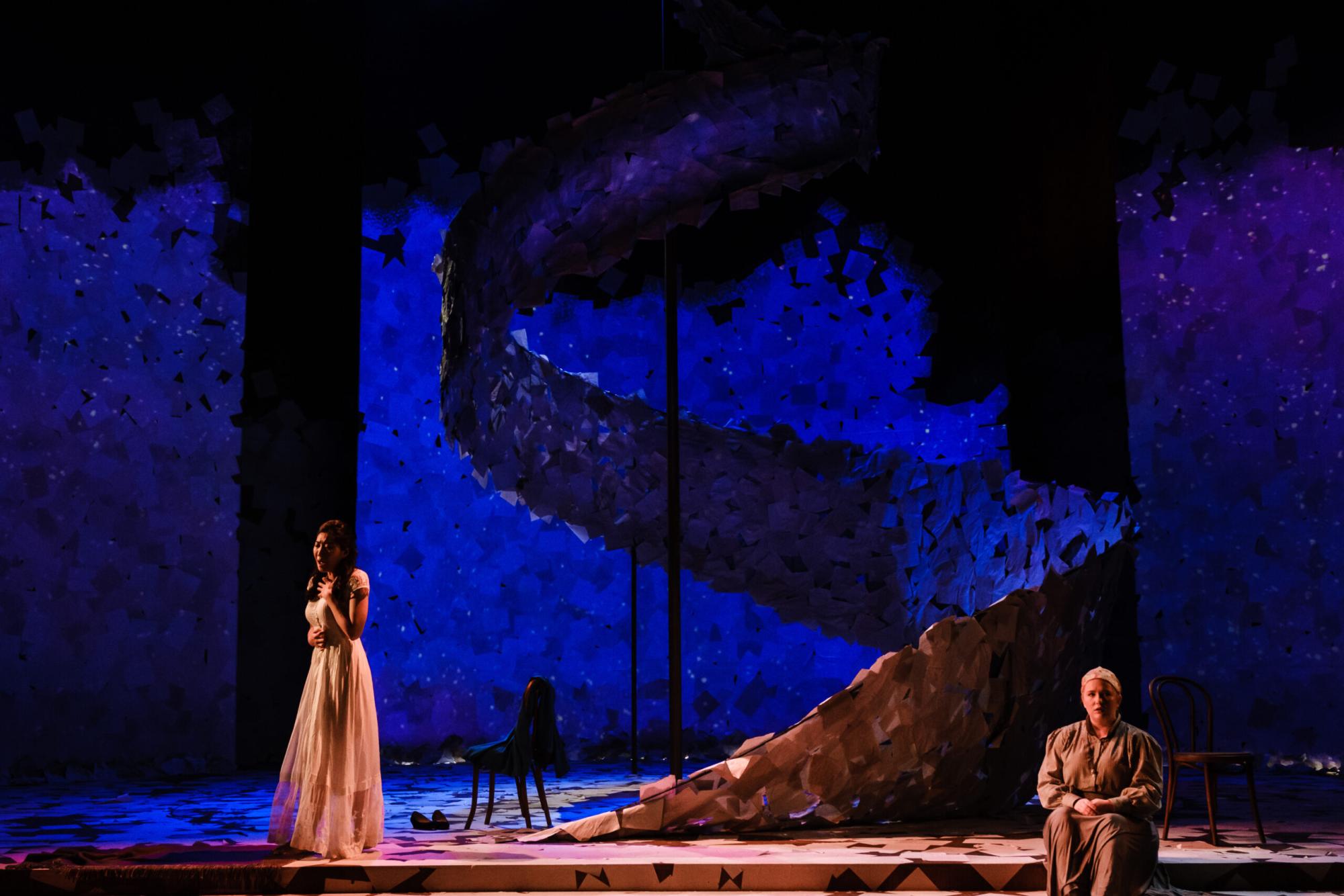 Two woman on stage amidst a wash of vibrant blue light