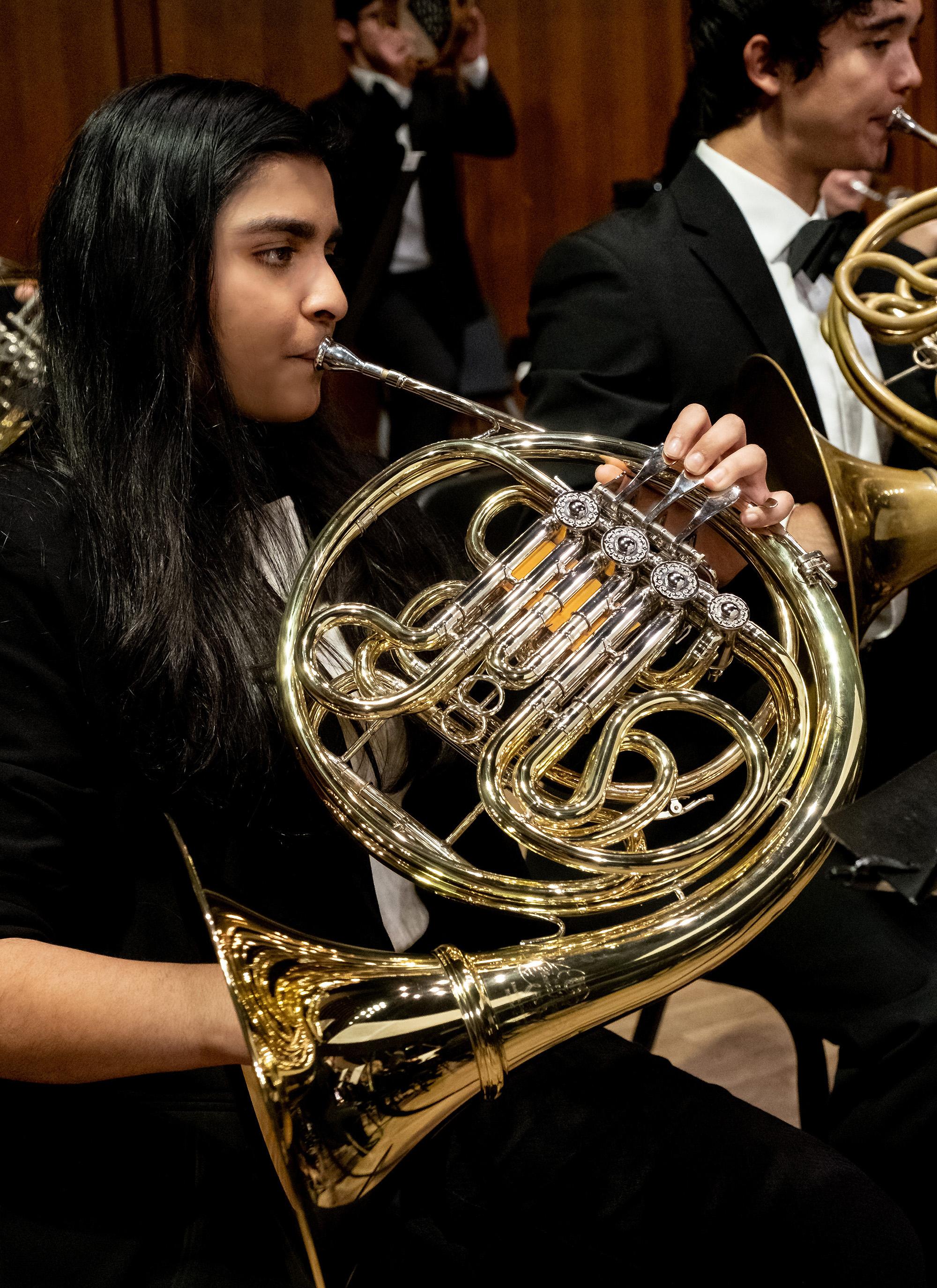 A horn player performs during an orchestra performance.