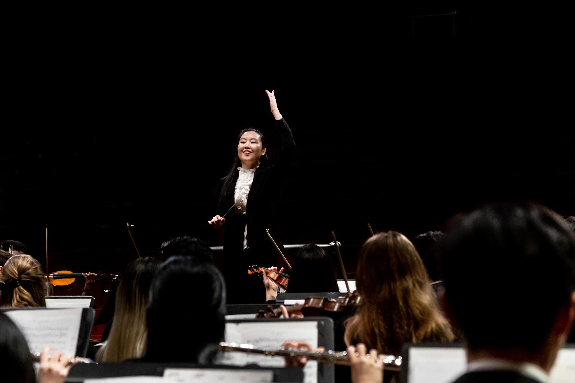 A female conductor leading the University Orchestra.