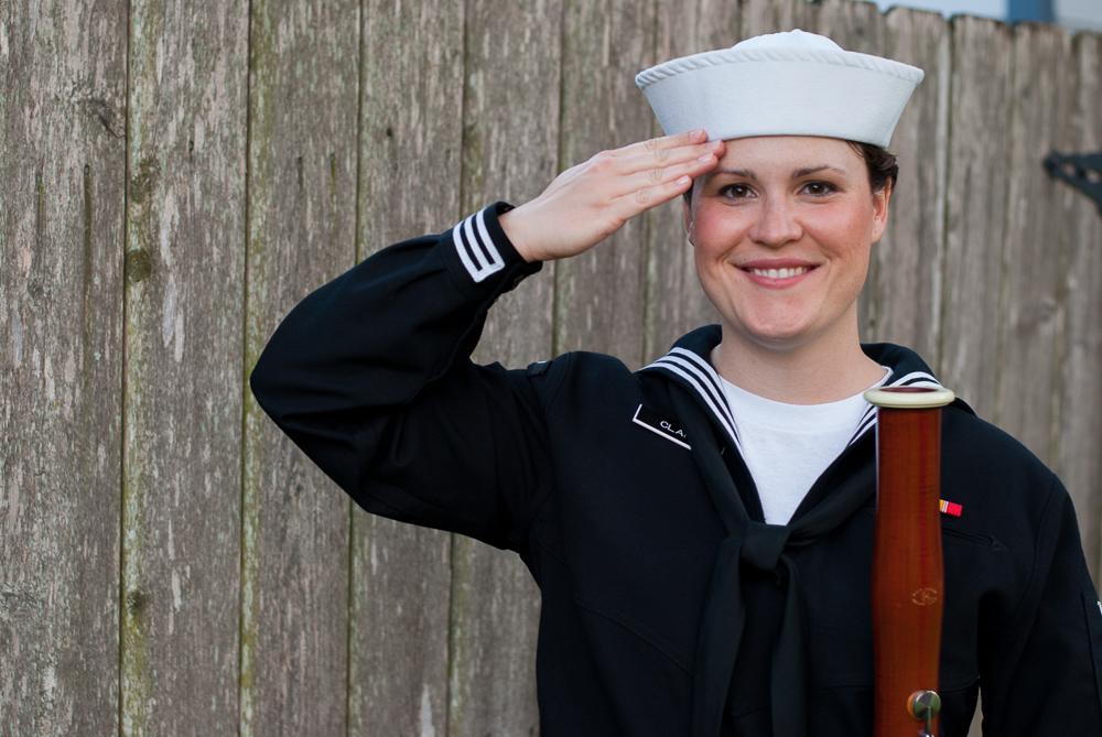 Katie Clark poses with a bassoon, wearing a Naval uniform and saluting