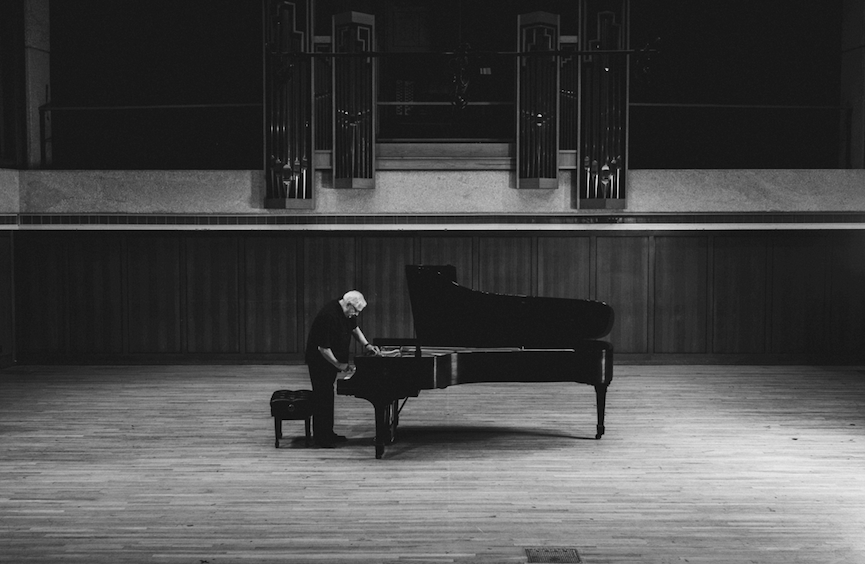 Charles Ball stands at a piano in Bates Recital Hall. Photo by Nathan Russell