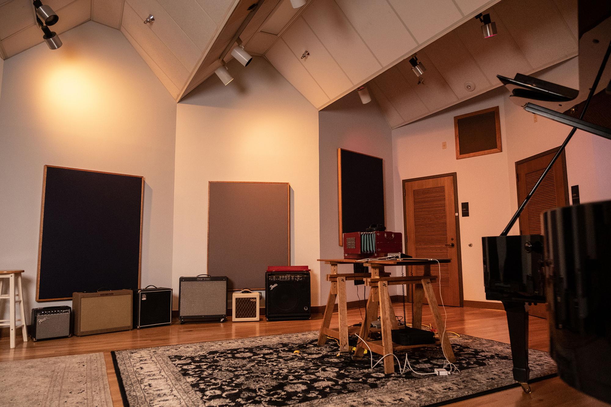 an intimate room with a grand piano and a line of amplifiers