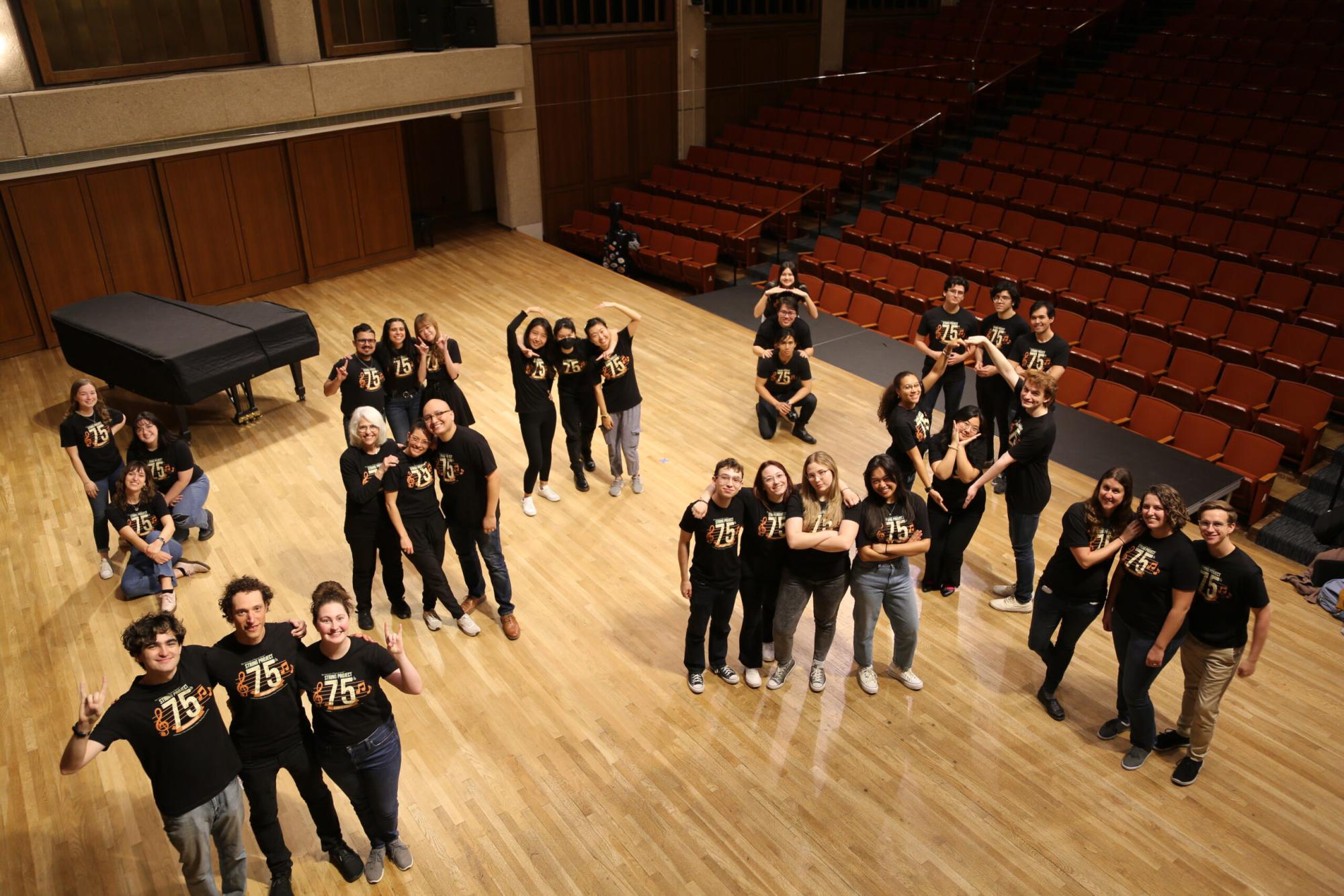 An image of the string project faculty posing casually for the camera on the Bates Recital Hall Stage