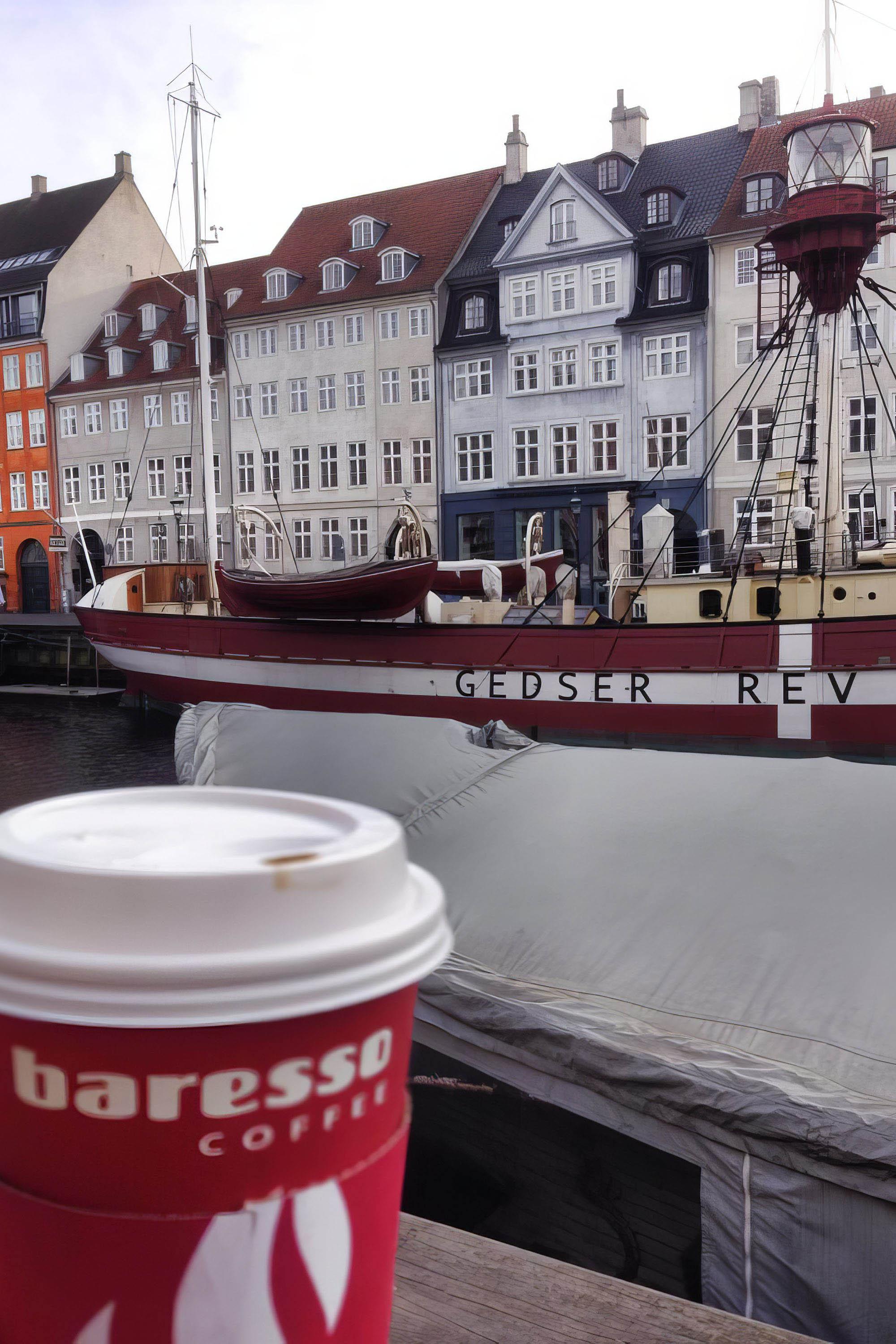 a ship in the harbor, in morning light. A coffee up is in the foreground of the photo