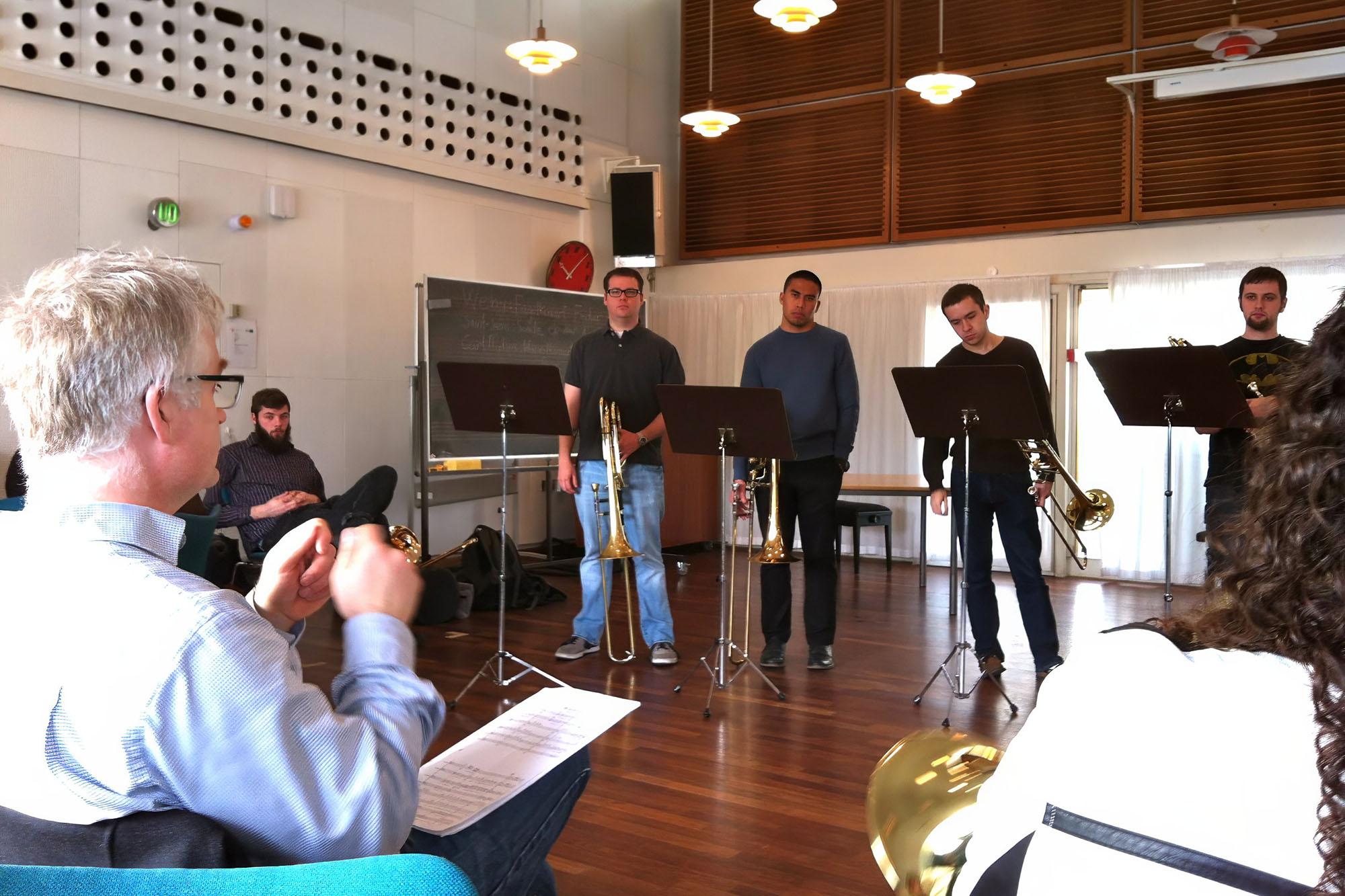 a group of students playing trombone for a small audience in an intimate setting