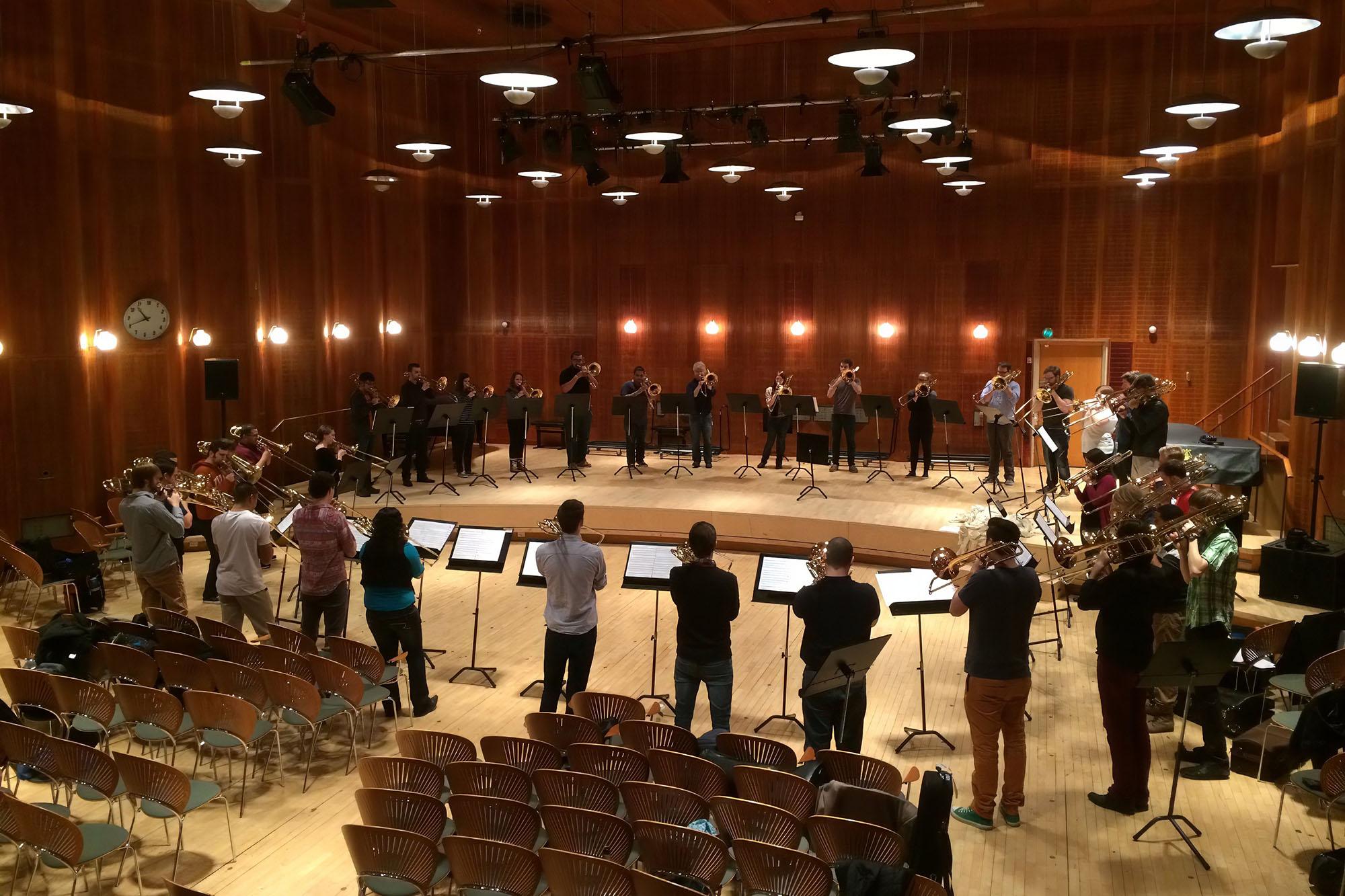 a group of trombonists play in a circle during a rehearsal