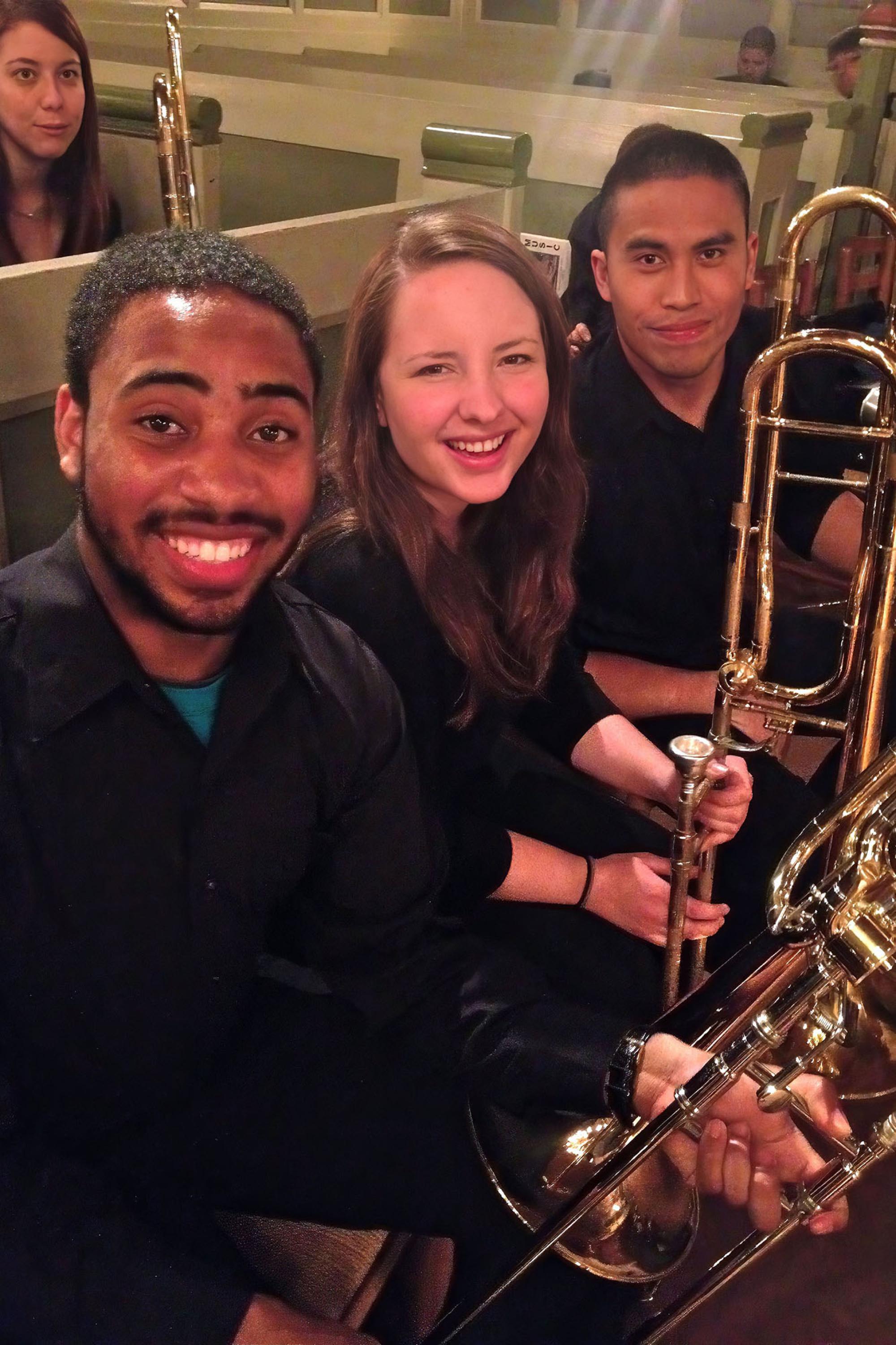 a few students smile for the camera while waiting for a concert to begin