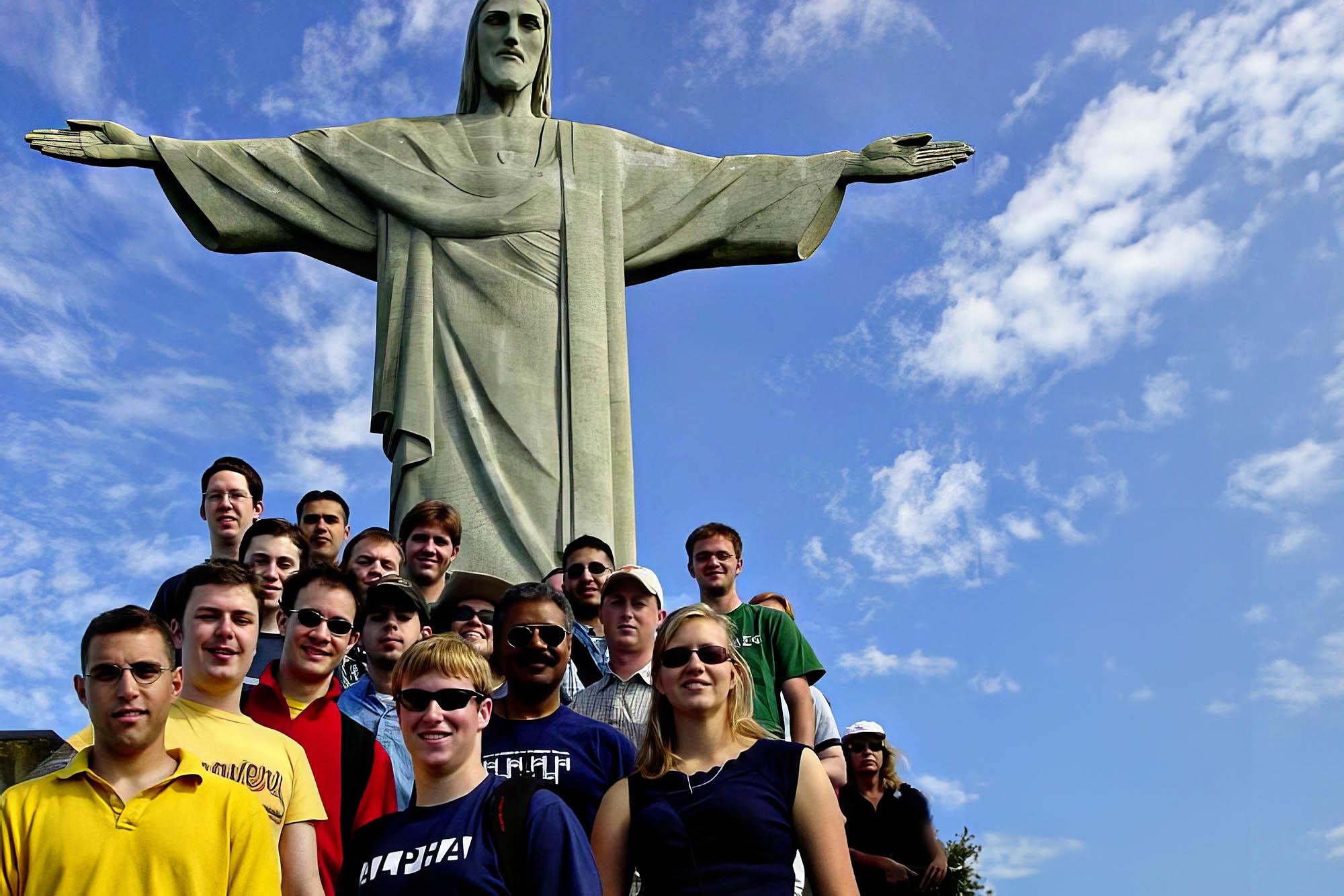 Trombone choir poses for a photo with the Christ the Redeemer statue towering behind them