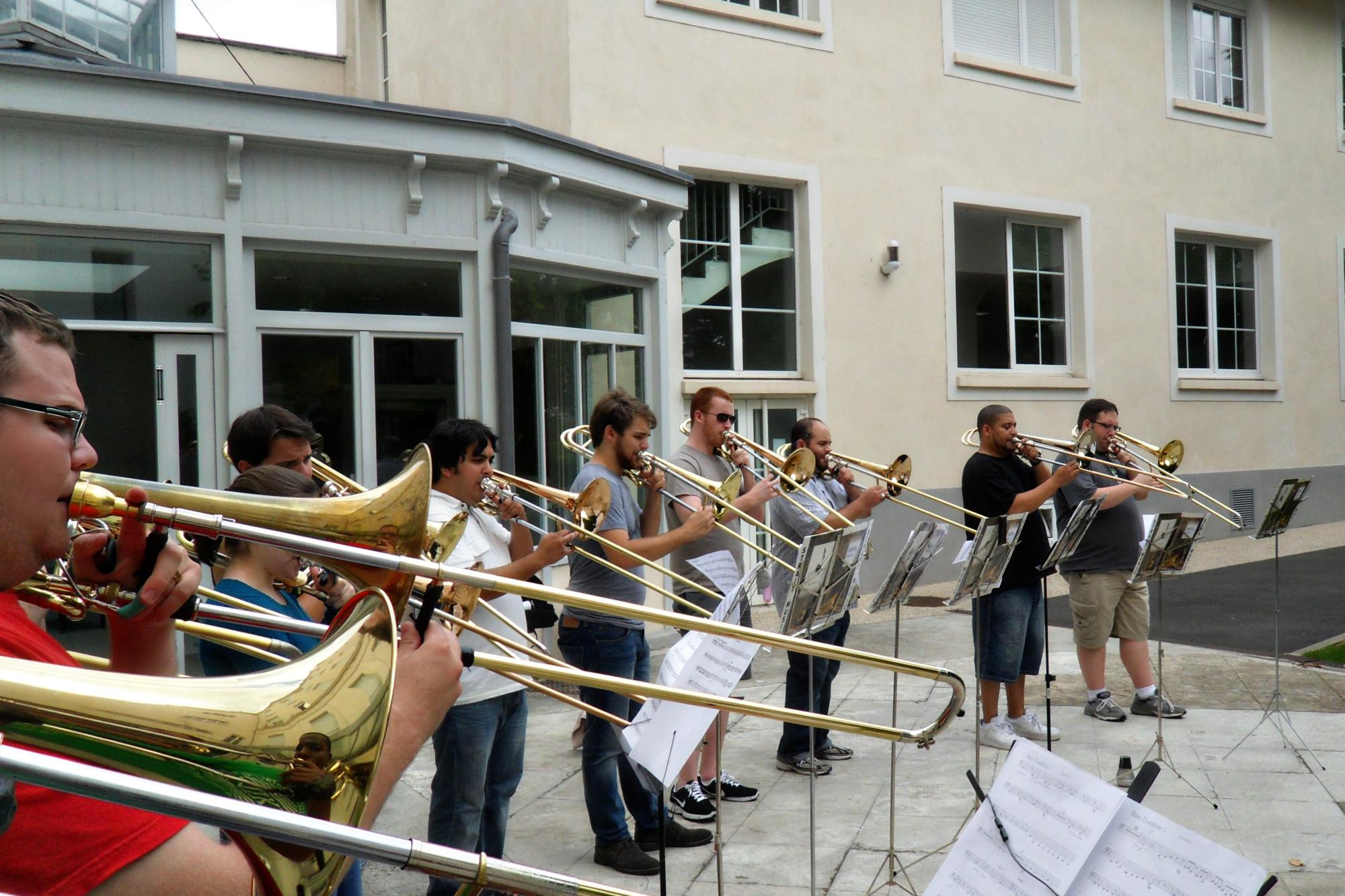 trombone choir performs outside in a courtyard 