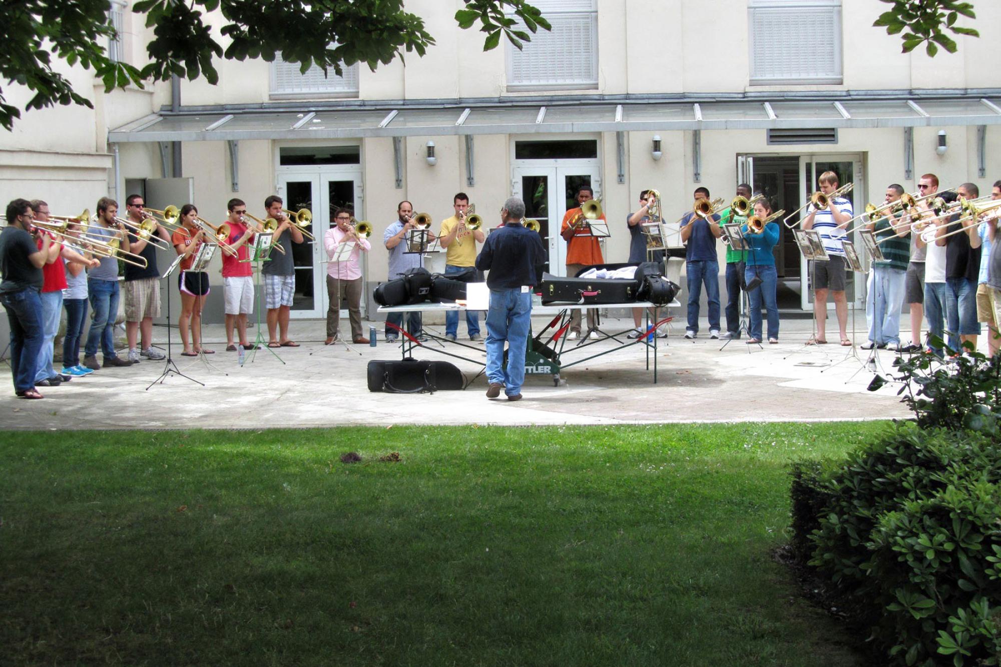 trombone choir performs in a grassy courtyard