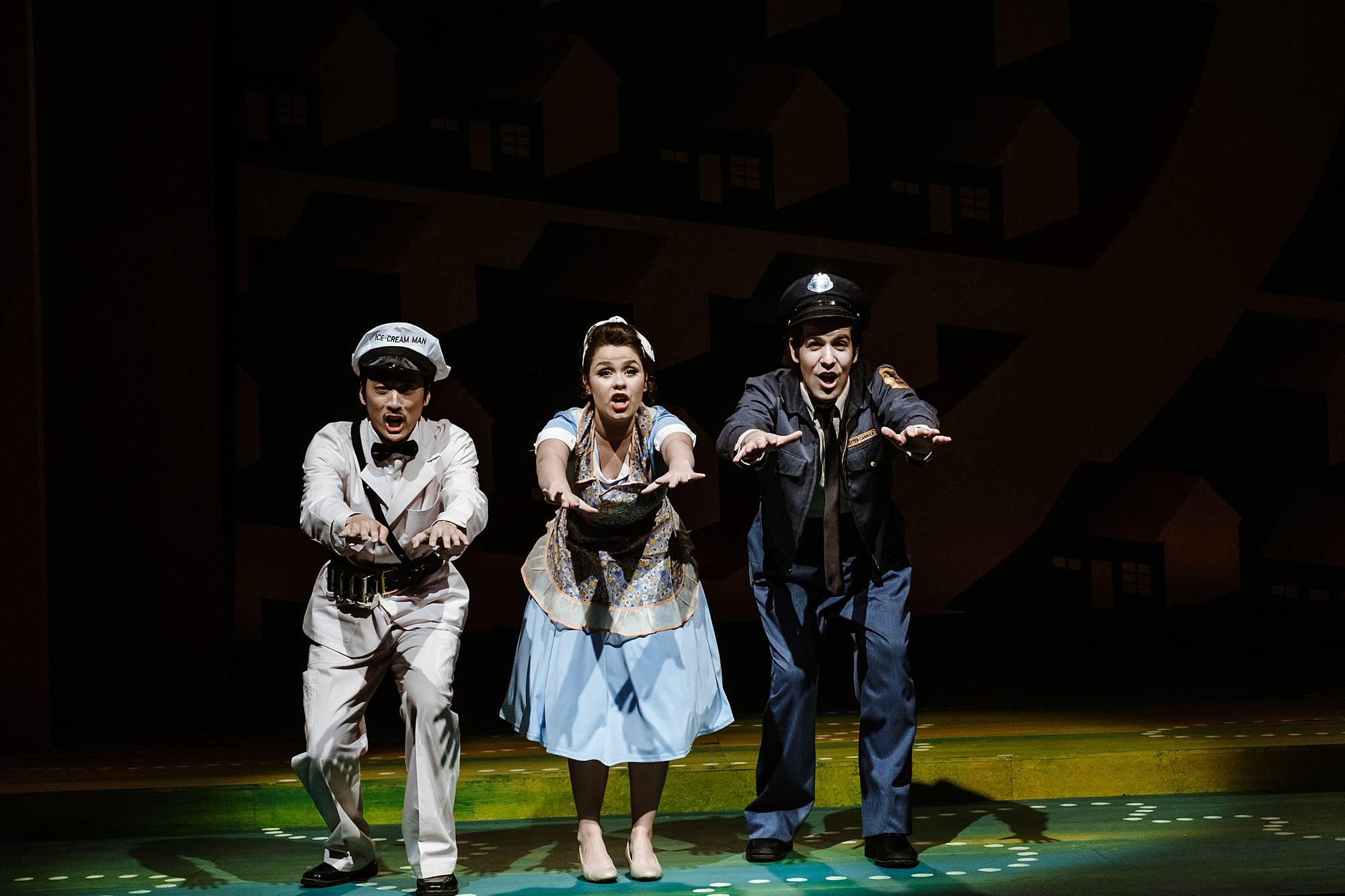 A milkman, maid and post office worker stand center stage, hunched over, arms in front of them during a dance number.