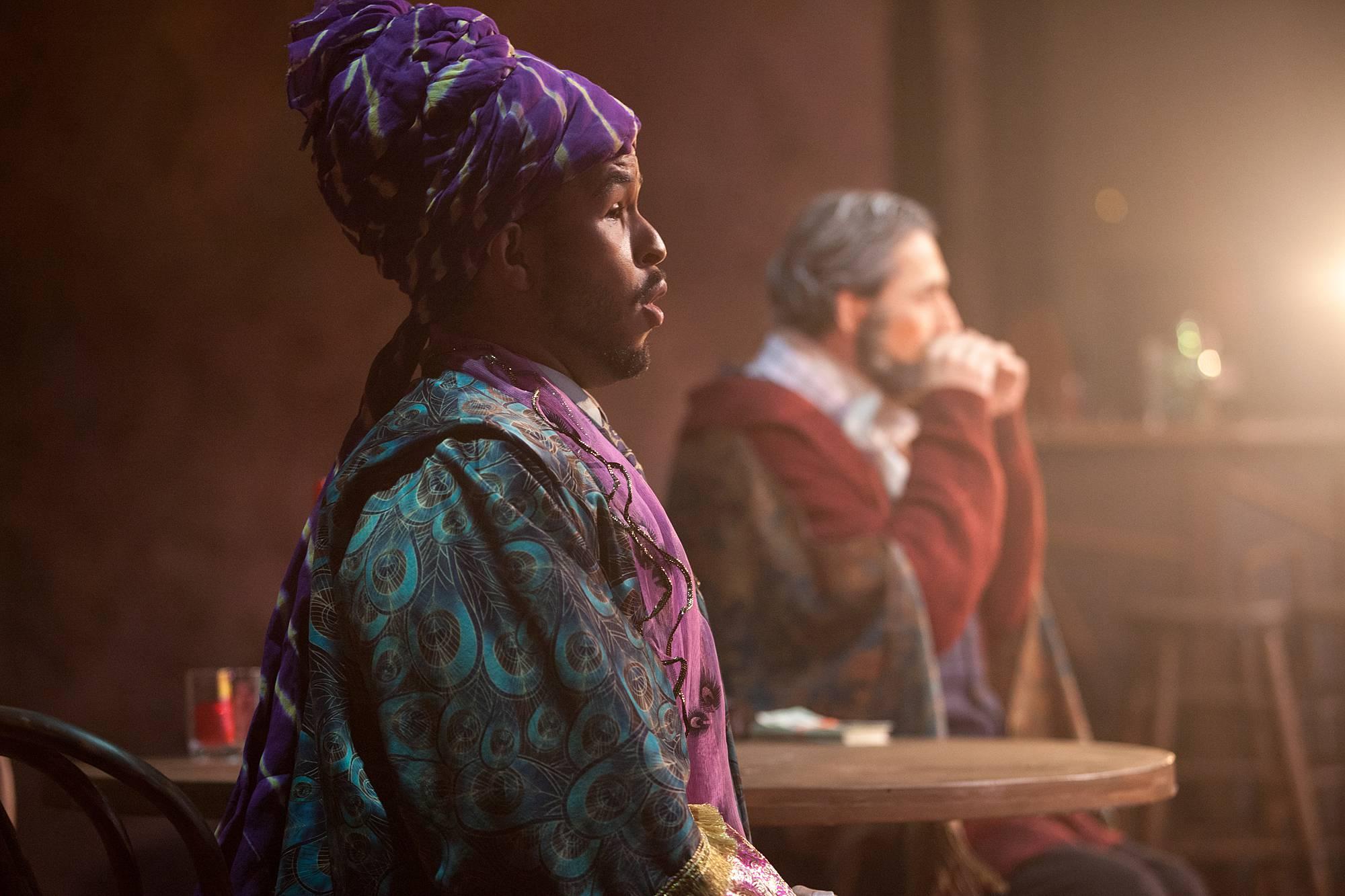 two men sit at a bar table gazing off into the distance.