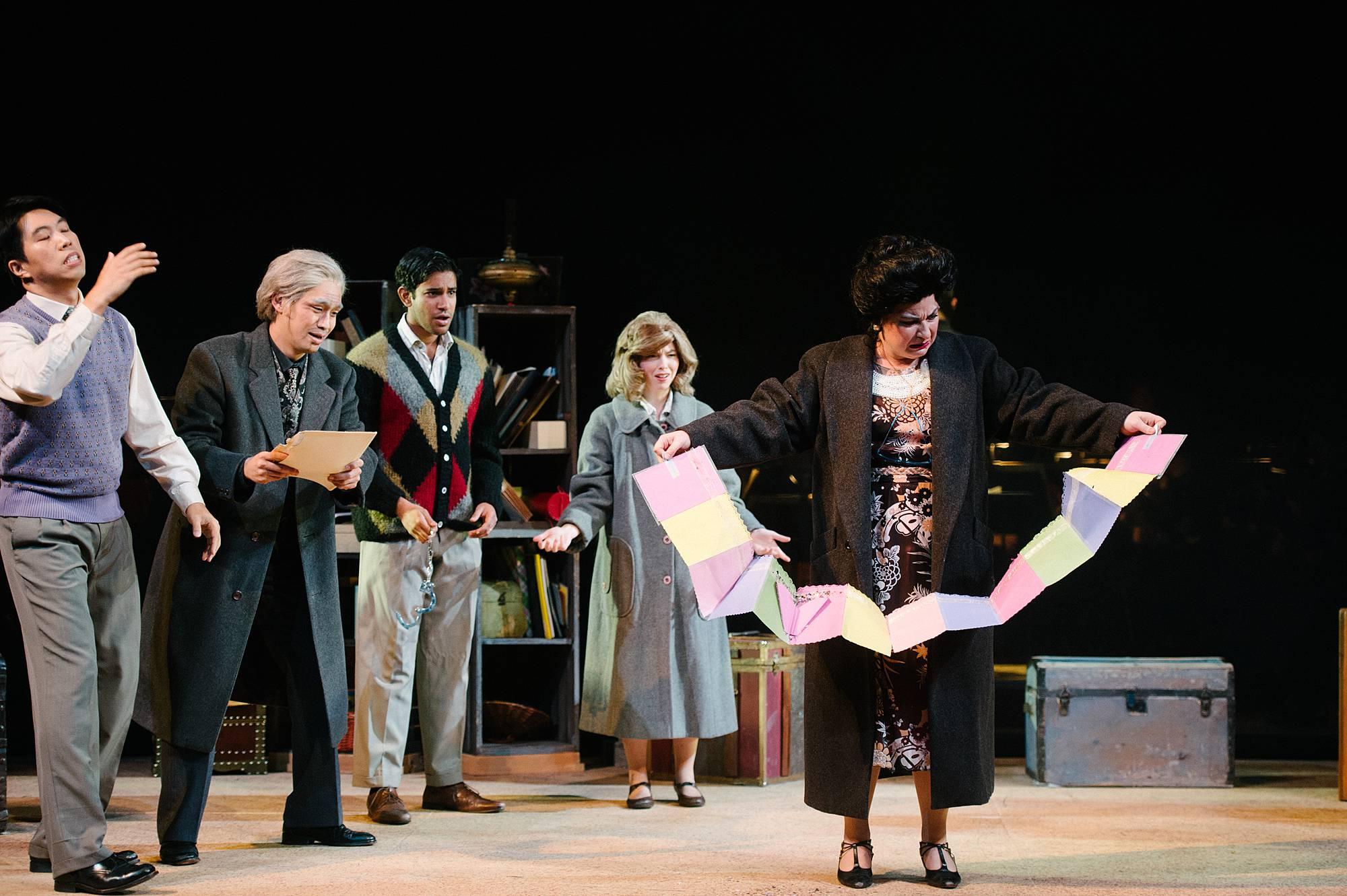 A woman unfolds an accordion-folded map, and it droops down toward the floor.  She looks perplexed like shed doesn't know what to do with the colorful document.