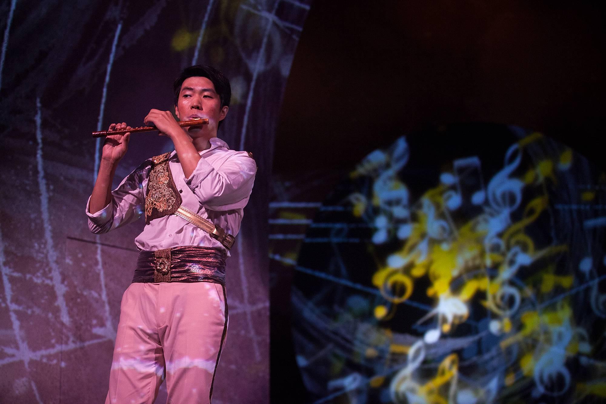 a man dress in a stately white uniform performs on his flute.