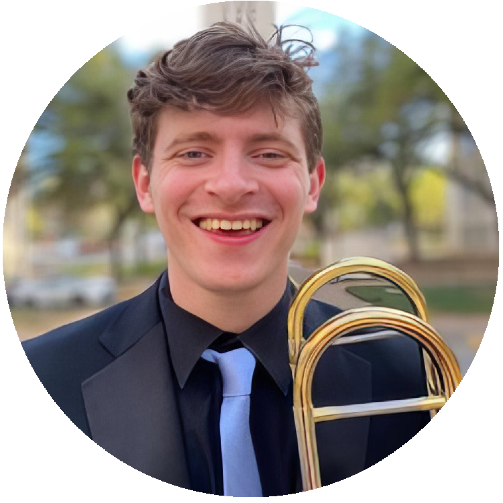 a headshot of Timothy Maines holding his trombone, with the UT tower behind him in the distance.