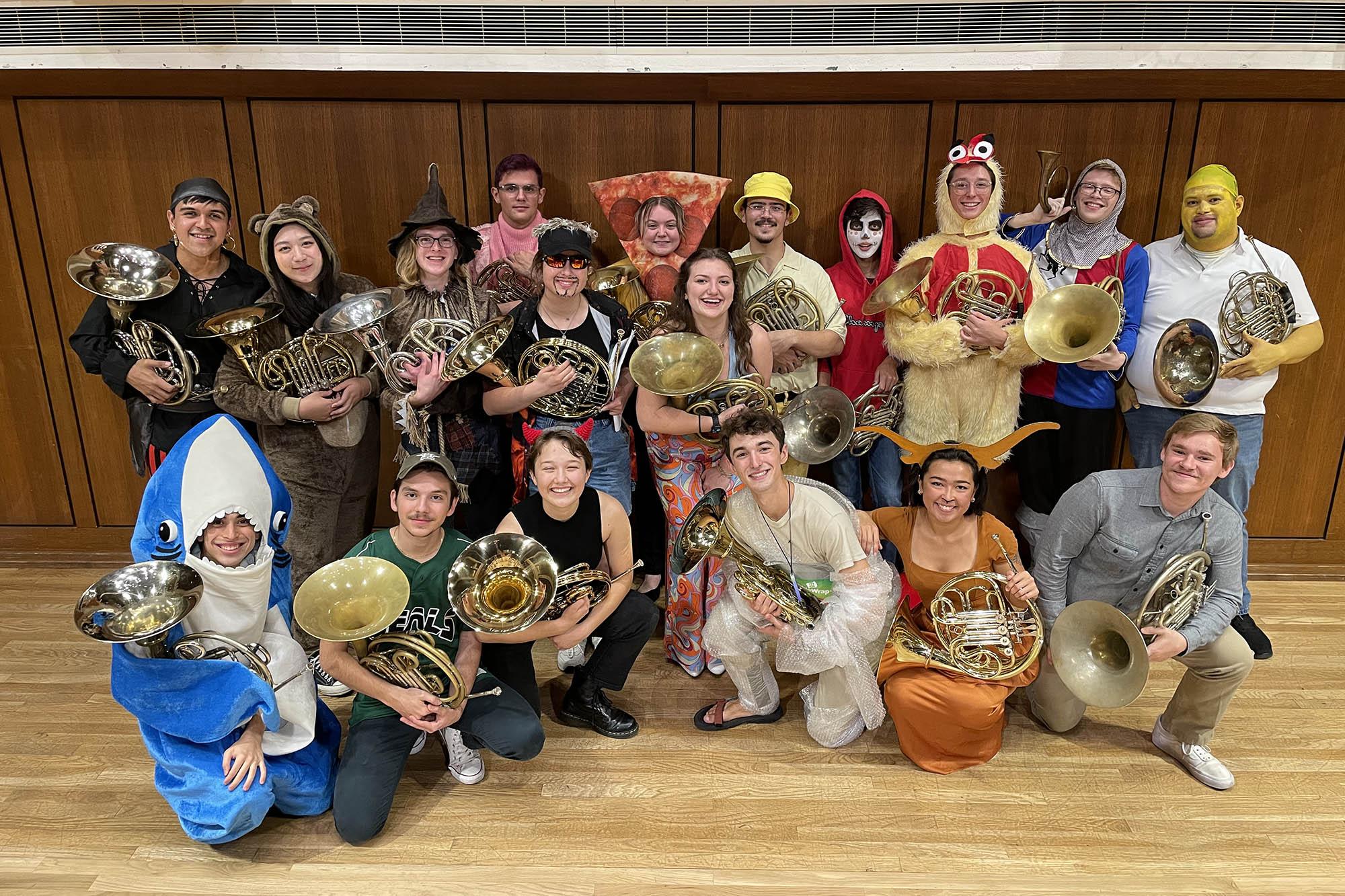 The horn studio, all dressed in Halloween costumes, pose for a group photo on the Bates Recital Hall stage after a concert.