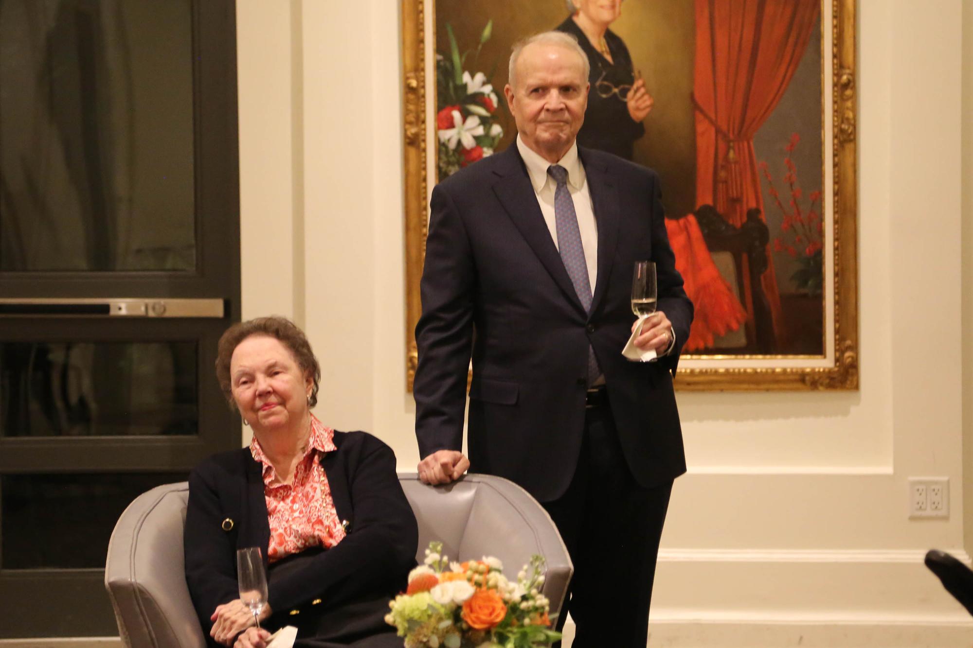 Dr. Larry Faulkner, Mary Ann Faulkner listen to a toast with wine glasses in their hands