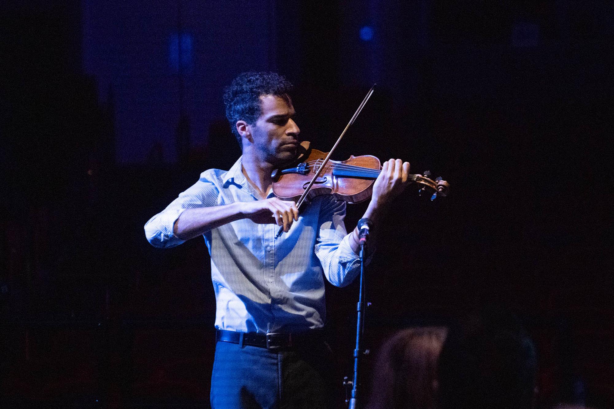 Violinist Patrice Calixte performs on a dark stage