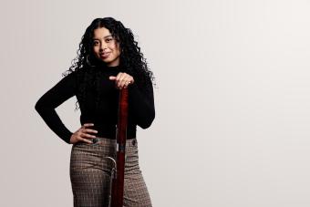 A female bassoonist with instrument looks into camera