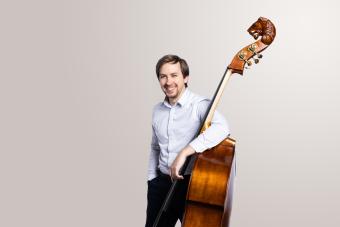 a student with a double bass smiling into camera.