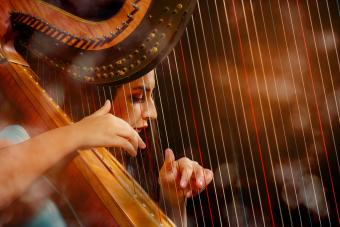 A close up of a harp player plucking the strings during a performance