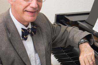 Michael C. Tusa sits at a piano in his office