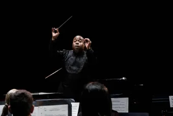 Cliff Croomes conducting the Symphony band, the darkened hall of Bates behind him.