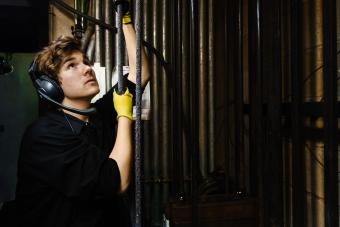 a student operates stage rigging back stage in a black box theater.