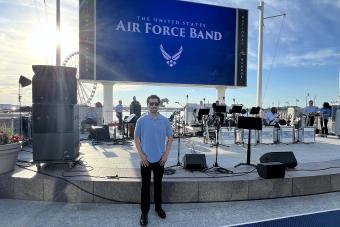  David Mesquitic on a ship with a stage and a Air Force Band sign in the background