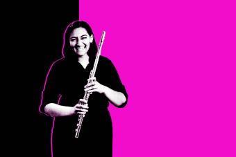 Black and white photo of a student holding her instrument in front of a black and magenta background.