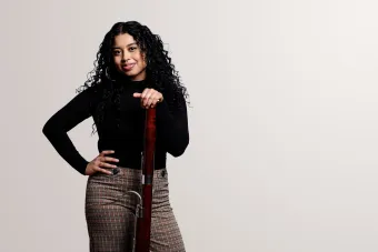 a student holds her bassoon and smiles into the camera