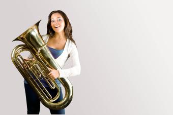 a student holds her tuba and smiles playfully