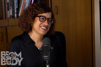 Jennifer Wilks sitting at a mic with a bookshelf behind her