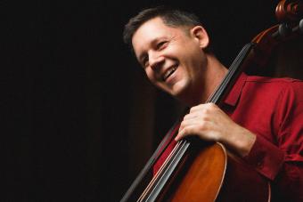 Nick Photinos with a cello on a black background