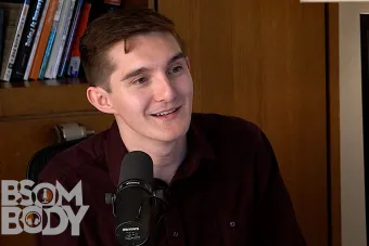 Saxaphonist Jacob Feldman sitting behind a mic with a bookshelf in the background