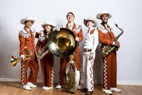 Smiling members of longhorn band pose with instruments
