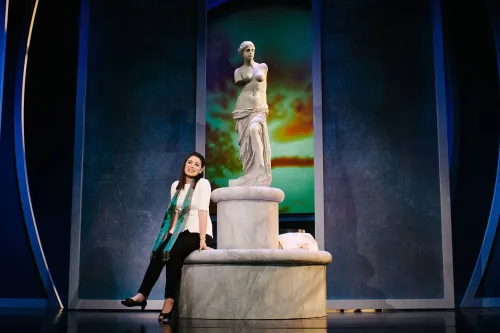 A woman sits at the Statue of Venus, looking off into the distance.