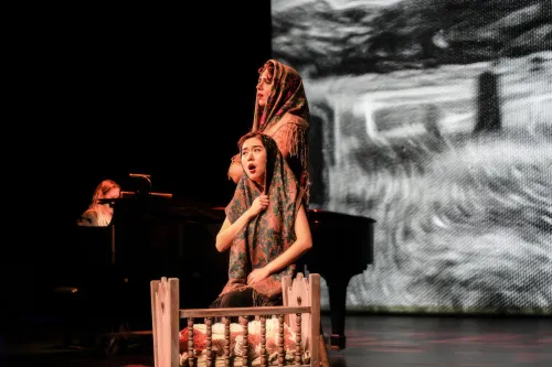 Two women with their heads covered by shawls perform on stage.