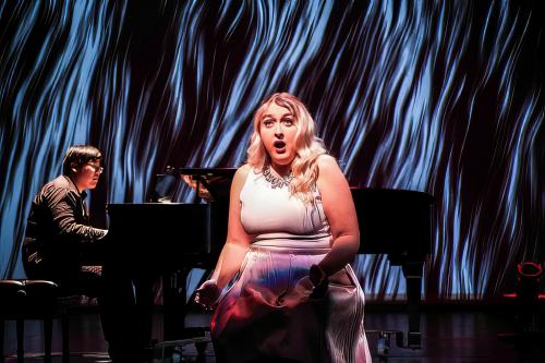 A singer performs in front of an underwater projected background