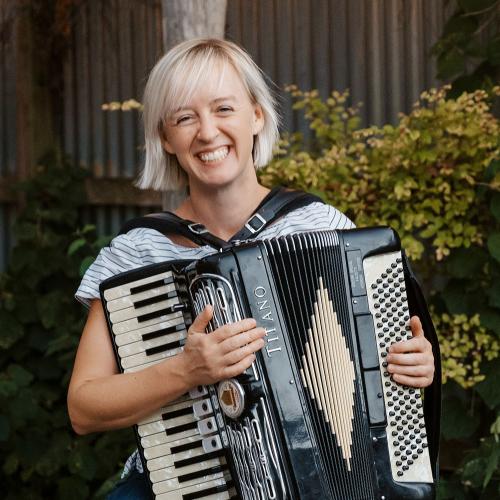 Chelsea Burns plays an accordion in an outdoor setting