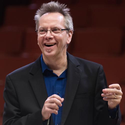 Jeff Hellmer smiles while conducting the Jazz Orchestra in a performance.