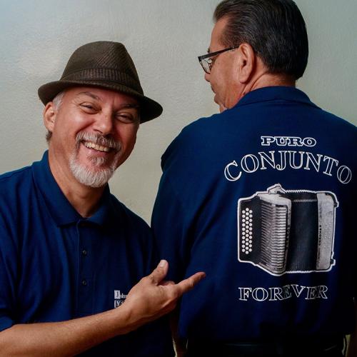 J.J. Barrera points to a person with their back to the camera, wearing a shirt that says “Conjunto, Forever" 