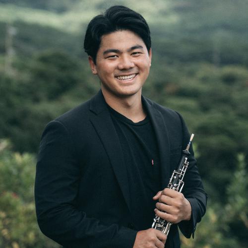 Ryan Hirokawa stands with his oboe, looking into camera