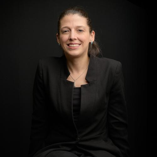a portrait of Gabriela Mora-Fallas, dressed in black, against a black background