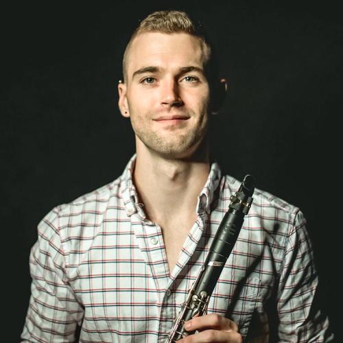 A headshot of Tyler Webster, holding his clarinet